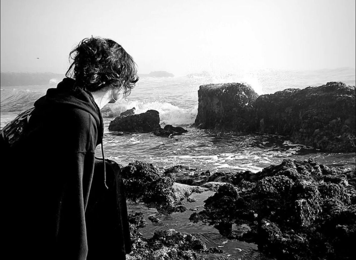 Black and white photo of a girl looking out towards the sea.